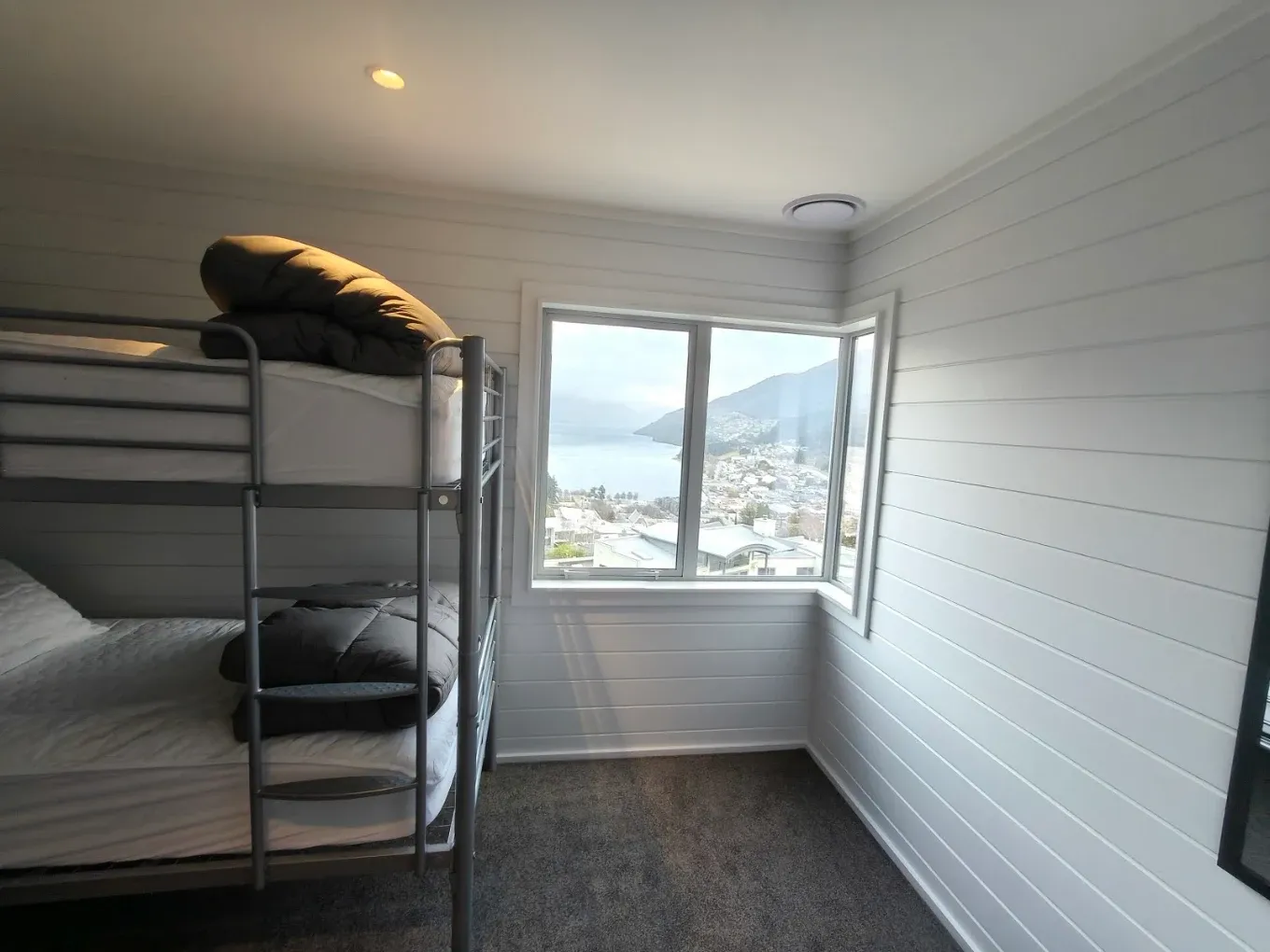 Bunk room painted white with a lake view