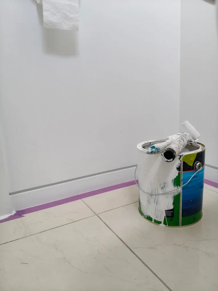 Paint kit and masking tape line in a corner mid-job